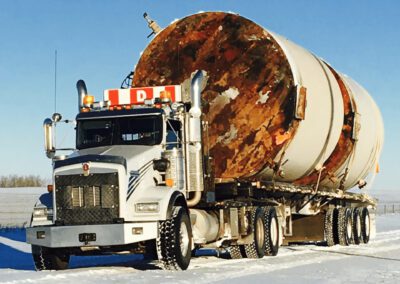 A large tanker truck travels along a snow-covered road, highlighting the challenges of winter driving